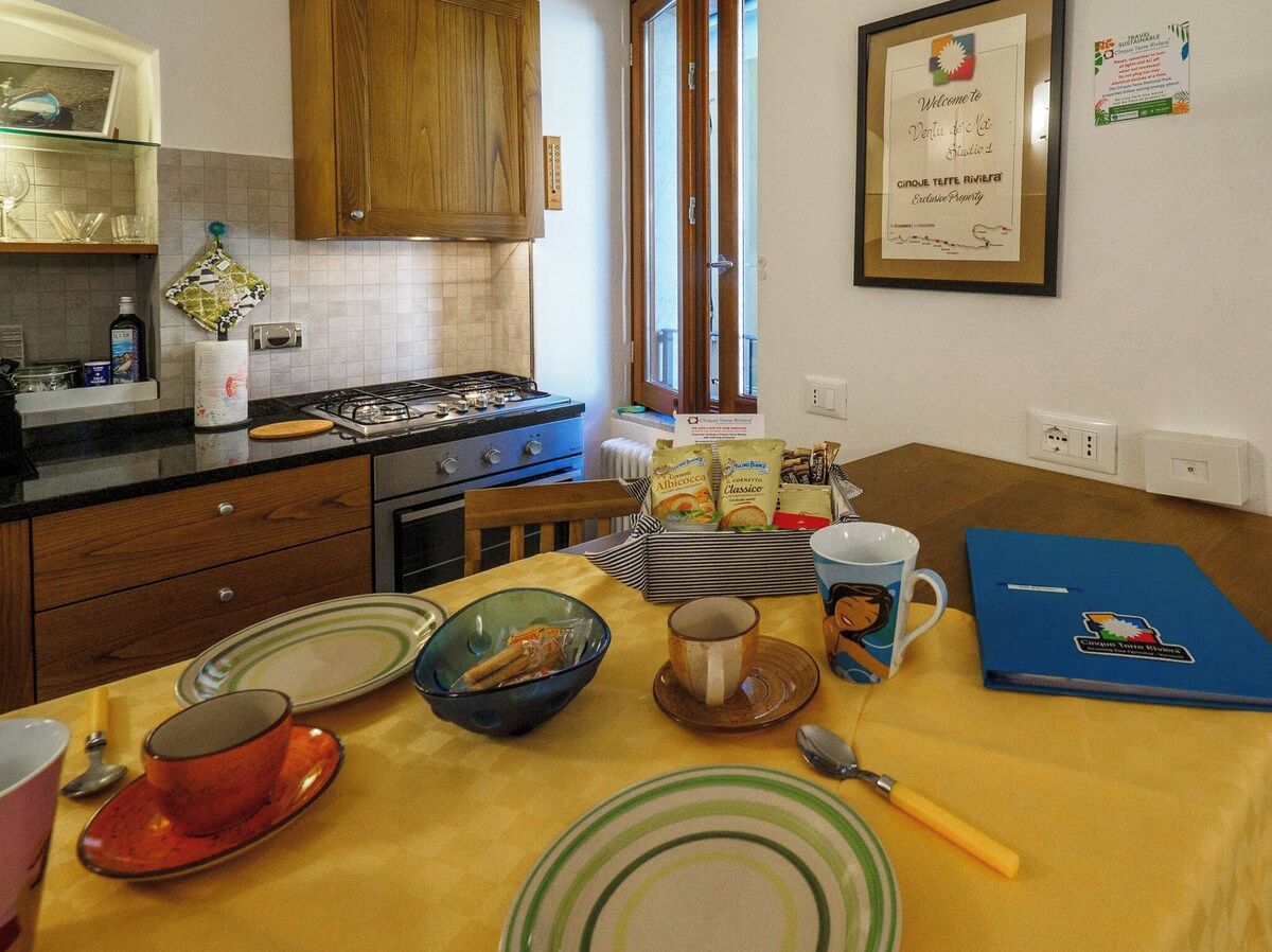 Una cucina con mobili in legno, un fornello a gas e un tavolo da pranzo apparecchiato con piatti, ciotole e una tazza.