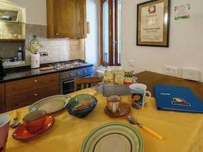 Une cuisine avec des meubles de rangement en bois, une cuisinière à gaz et une table à manger mise avec des assiettes, des bols et une tasse.