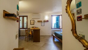Una habitación con un banco de madera, una mesa con sillas, un radiador y una ventana con vistas.
