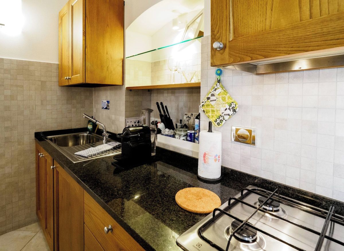 A kitchen with wooden cabinets, a granite countertop, a gas stove, and a stainless steel sink.