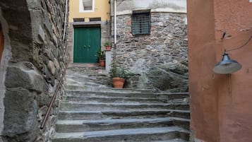 Una estrecha escalera de piedra que conduce a un edificio con una puerta verde y una ventana con contraventanas.