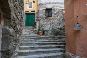 Eine enge Steintreppe führt zu einem Gebäude mit einer grünen Tür und Blumentöpfen.