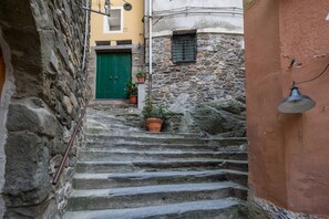Eine enge Steintreppe führt zu einem Gebäude mit einer grünen Tür und Blumentöpfen.