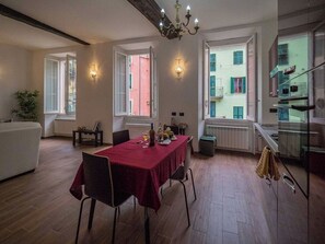 Un comedor con una mesa dispuesta para dos, una araña y vistas a un edificio con balcones.