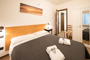 Une chambre d’hôtel avec un lit, une table de chevet, une chaise, une armoire et un tableau au mur.