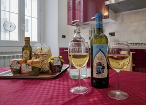 Un ambiente de cocina con una botella de vino, dos copas de vino blanco y una bandeja de comida.