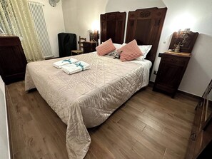 Una habitación de hotel con una cama grande, cabecera de madera y suelo de madera.