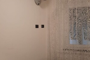 A plain wall with two black electrical switches and a patterned window blind.
