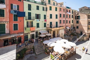 A courtyard with outdoor seating, a staircase, and a variety of buildings with different architectural styles. - Tedea Apartment with Ac (Vernazza)