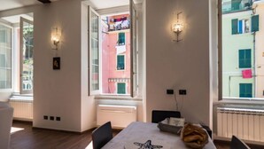 Uma sala de jantar com mesa, cadeiras, uma decoração de estrela-do-mar e uma janela com vista para um edifício.