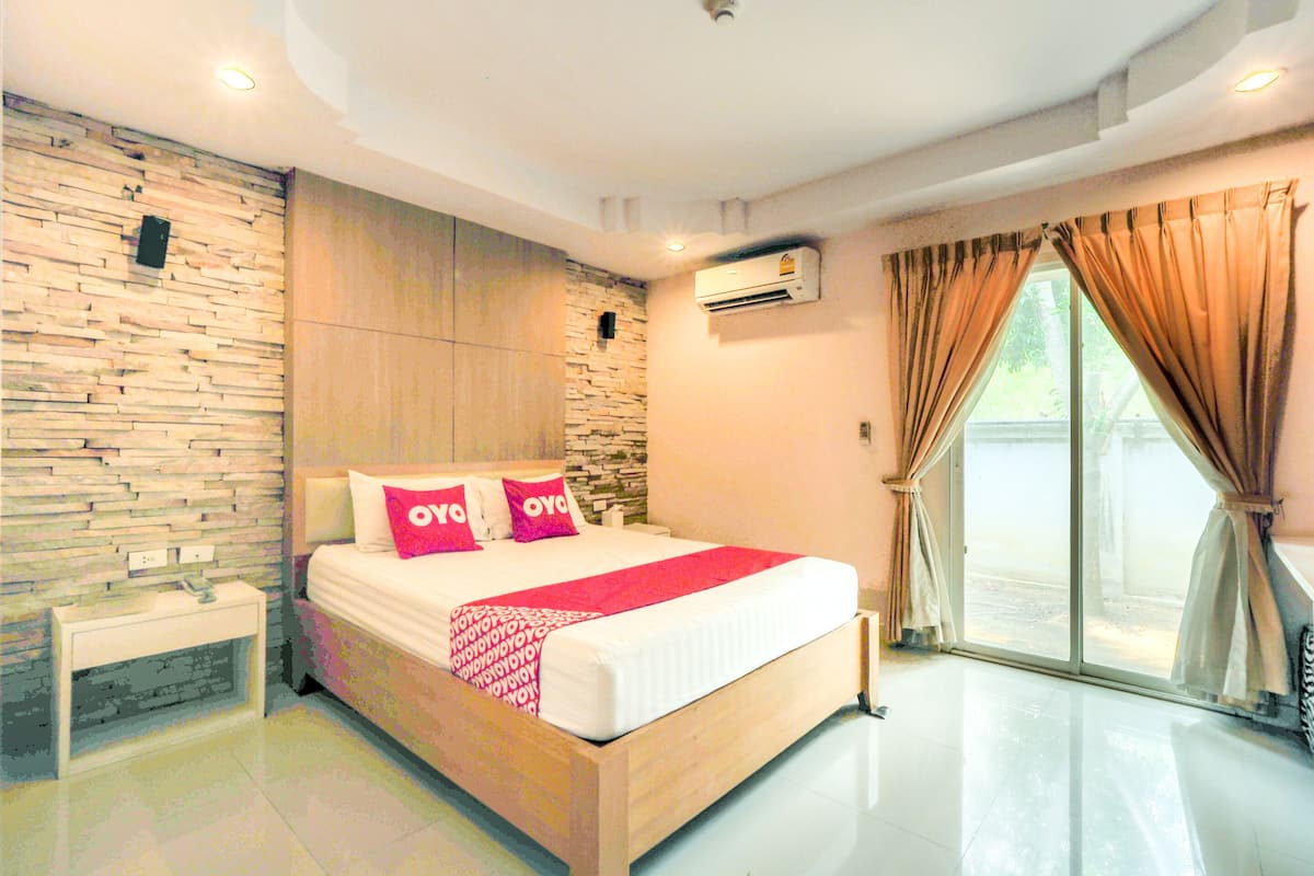 A modern bedroom with a stone wall, a wooden bed, a nightstand, and a large window with curtains.