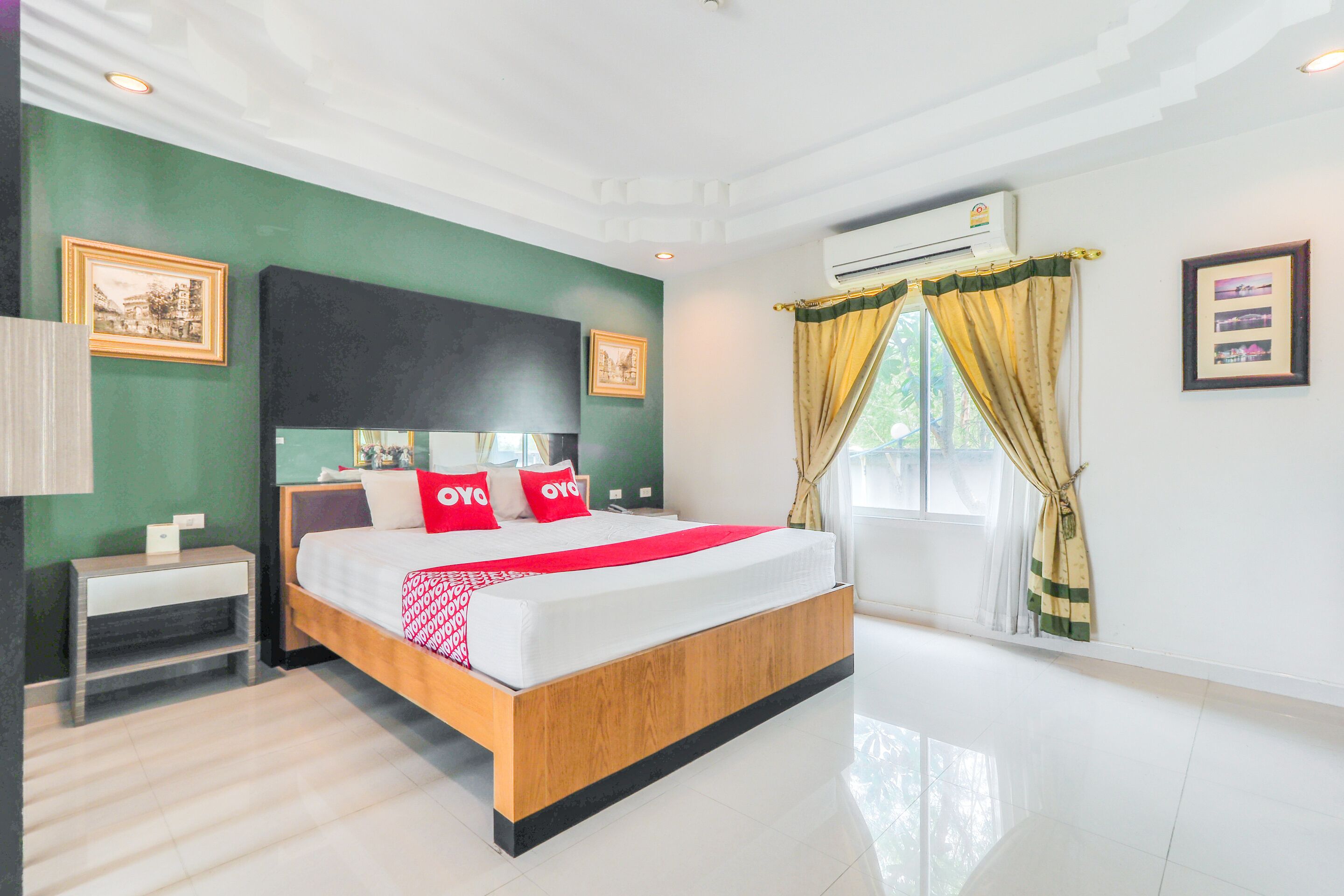 A modern hotel room with a large bed, a nightstand, a wall-mounted air conditioner, and a window with curtains.