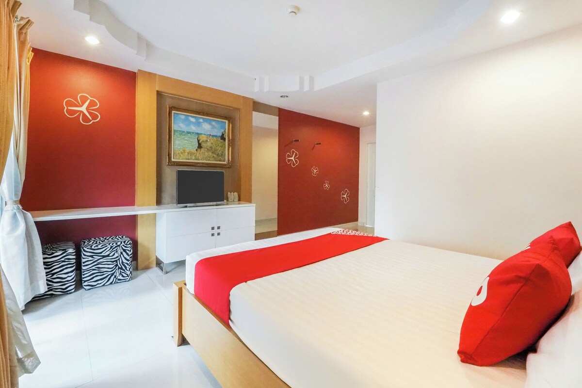 A modern bedroom with a bed, a TV, and a painting on the wall.
