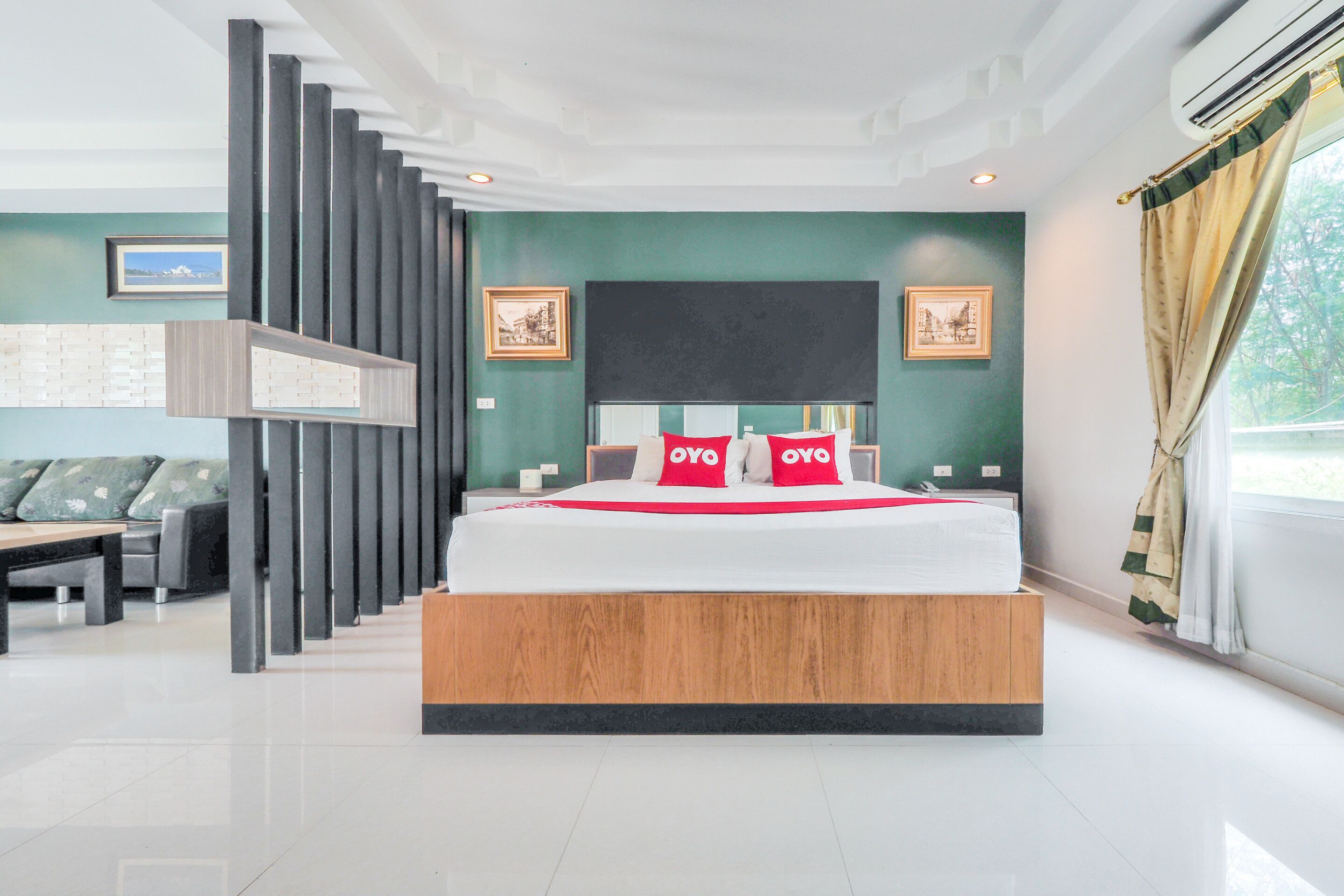 Un dormitorio moderno con una cama grande, una plataforma de madera, paredes verdes y vistas al exterior.