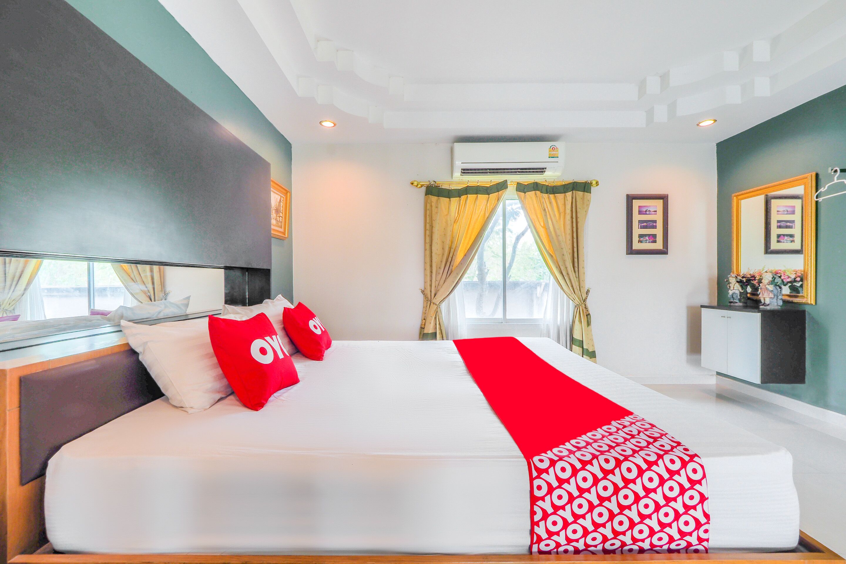 A hotel room with a large bed, a bedside table, a mirror, and a window with curtains.