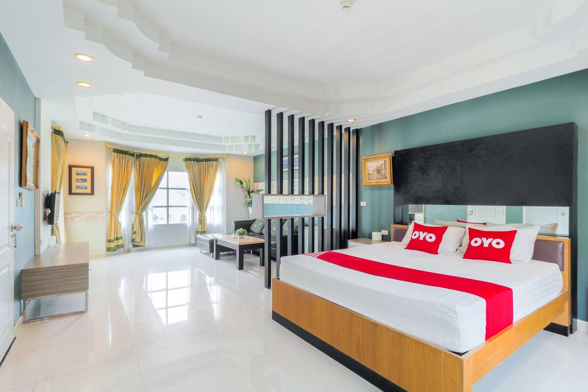 A modern hotel room with a large bed, a TV, and a desk.