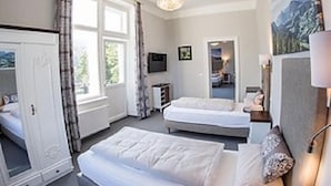 Habitación de hotel con dos camas, televisión, un cuadro y ventana con cortinas.