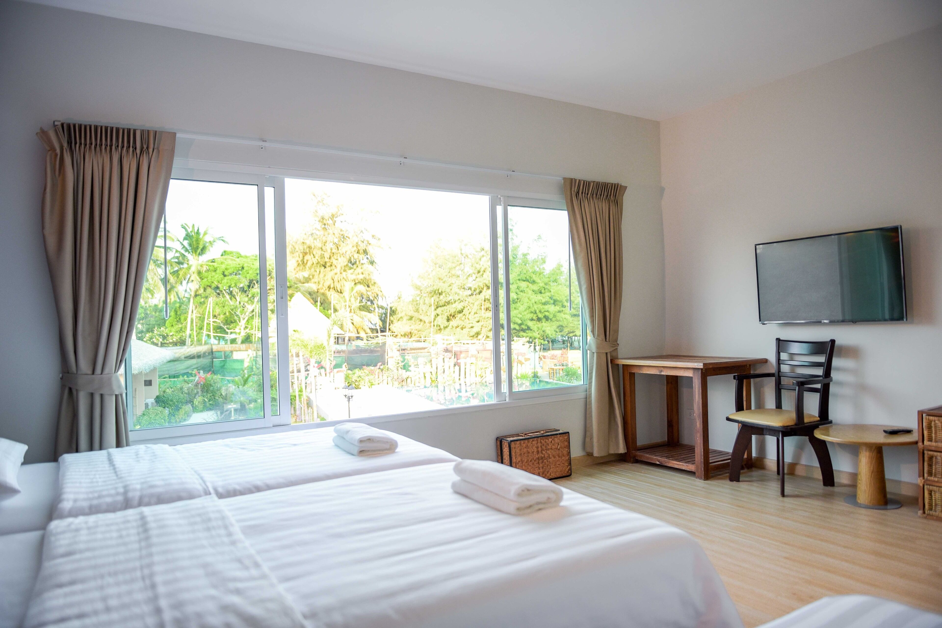 Una habitación de hotel con dos camas, televisión, una mesita y una silla.
