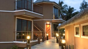 Um resort com entrada central, várias varandas e estrutura com telhado de palha.
