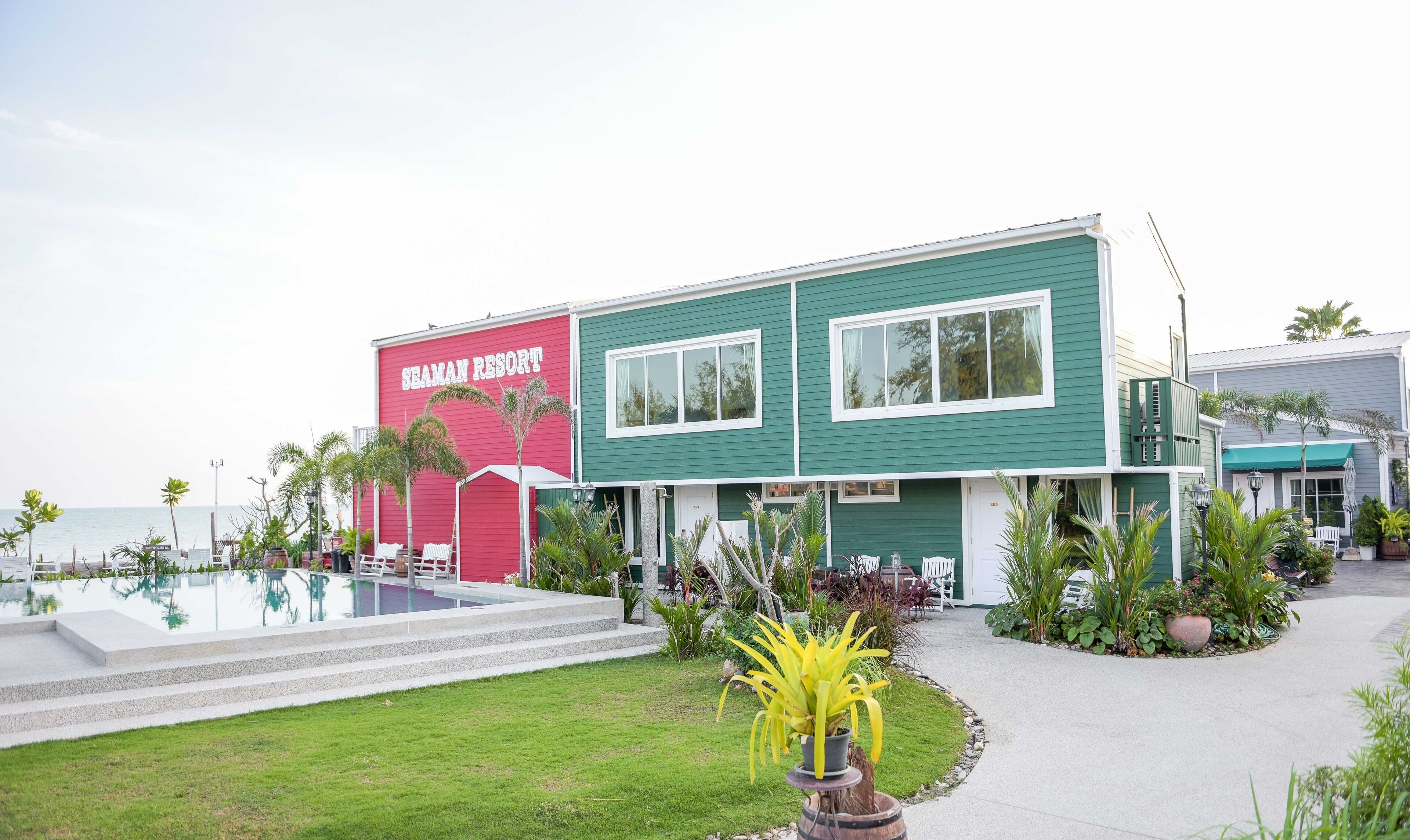 A two-story building with a pool, labeled "SEAMAN RESORT," surrounded by tropical plants and palm trees.