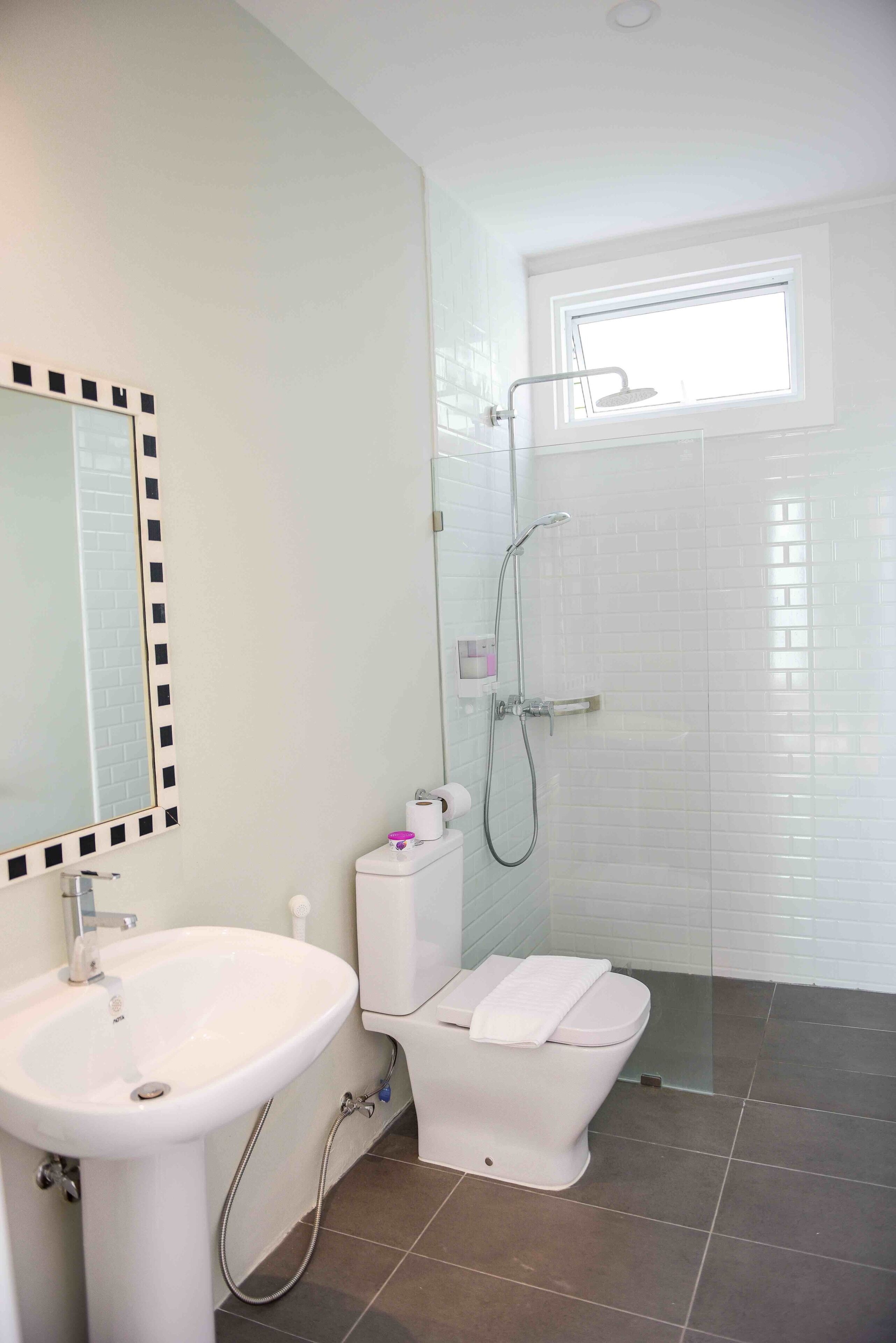 A bathroom with a white sink, toilet, and shower.