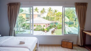 Quarto com uma grande janela, uma cama e uma mesinha.