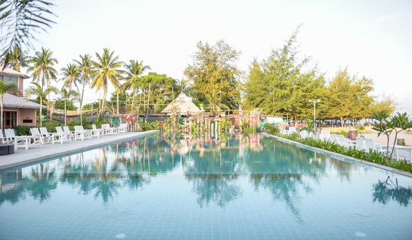 Une piscine avec des chaises longues et des palmiers.