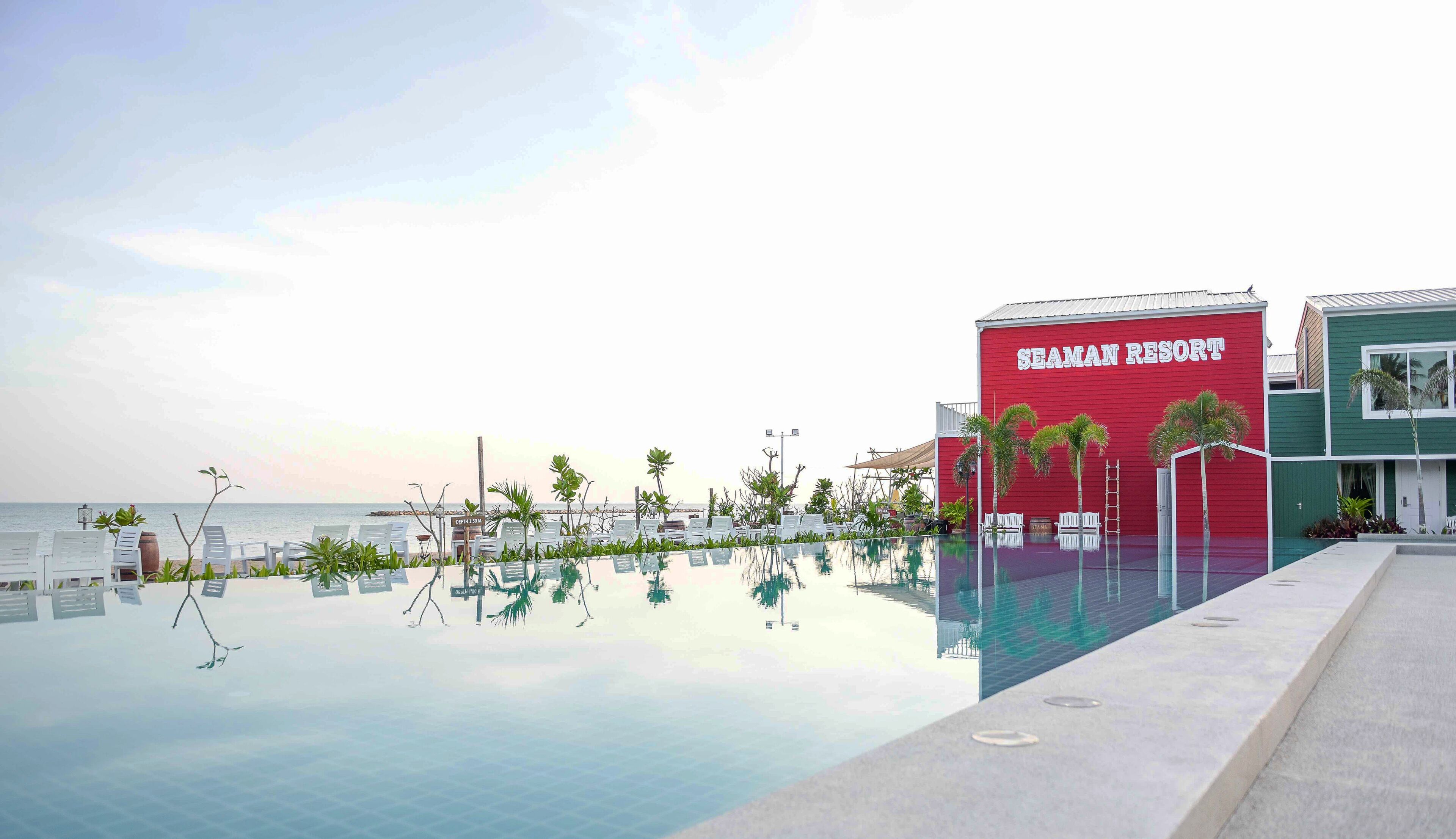 A resort with a clear pool, lounge chairs, and a building labeled "SEAMAN RESORT".