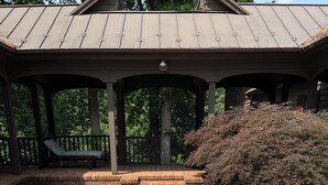 A hot tub in a covered outdoor area with a brick patio and a wooden pergola overhead. - 12-Person House with Hot Tub on Spectacular Estate (Castleton)