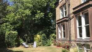A garden with a lawn, two striped lounge chairs, and a brick building with large windows.