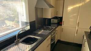 A compact kitchen with a sink, stove, oven, and microwave.