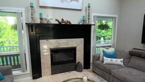 Un salon avec une cheminée, un canapé, une table basse et un tableau au mur.