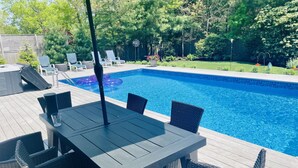 Un espace aménagé au bord de la piscine, avec une table et des chaises, un jacuzzi et des chaises longues.