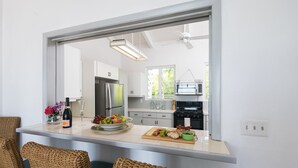 A modern kitchen with a large island, white cabinetry, and a view into the dining area. - Beautiful, Spacious two bedroom Ocean View Villa (providenciales)