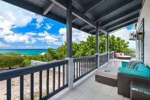 A covered outdoor seating area with a view of the ocean and beach.