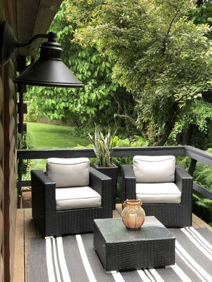 An outdoor patio with wicker furniture, a lamp, and a potted plant.