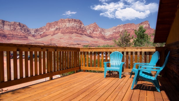 Une terrasse en bois avec deux chaises bleues, offrant une vue sur des formations rocheuses rouges.