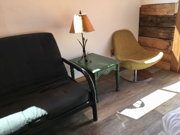 A room with a black sofa, a green table with a lamp, and a yellow chair.