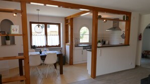A modern kitchen with white cabinets, a wooden island, and a dining area with a table and chairs. - Vacation apartment Schwarzwaldliebe near Freiburg, terrace (Bollschweil)