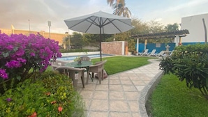 A patio with a table and chairs, a pool, and a garden with various plants. - Hotel Pez Vela Manzanillo (Manzanillo)