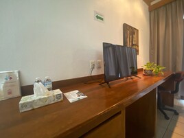 Balcão de recepção com monitor de computador, planta em vaso e caixa de lenços.