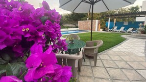 A patio area with a pool, lounge chairs, and a table with chairs. - Hotel Pez Vela Manzanillo (Manzanillo)