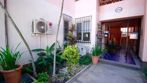 A courtyard with a small garden, an air conditioning unit, and a building entrance with a sign. - 50% of Monthly 35% weekly  (Versalles)