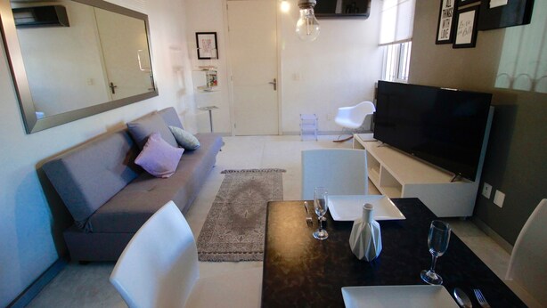 A modern living room with a sofa, dining table, and TV. - 50% of Monthly 35% weekly  (Versalles)