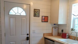A compact kitchen with white cabinetry, a built-in dishwasher, and a red toaster.