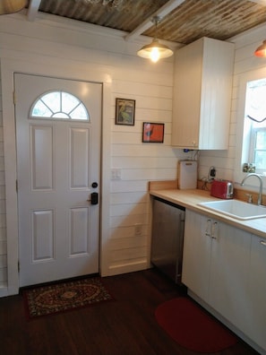 A compact kitchen with white cabinetry, a built-in dishwasher, and a red toaster.