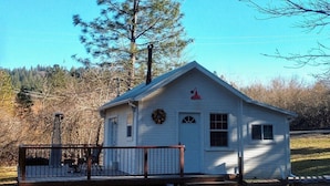 A small white cabin with a porch, a chimney, and a wreath on the door.