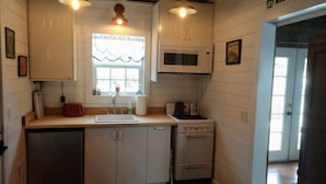 A kitchen with white cabinets, a sink, a stove, and a microwave.