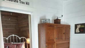 A room with a bed, a wooden cabinet, and a sign indicating 'Madrone Tree Hill'.