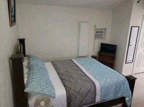 Cozy retreat with a single bed, nightstand, and TV, complete with a patterned bedspread and quilted blanket.